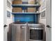 Modern laundry room with blue accent wall, floating shelves, decor, and front-loading washer and dryer at 3306 Emory Dr, Marietta, GA 30062