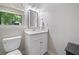 Powder room with toilet, vanity, modern mirror, and natural light from a window with green view at 3306 Emory Dr, Marietta, GA 30062