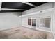 Open-concept living room with carpet, white walls, sliding screen doors, and black ceiling beams at 5800 Mitchell Rd, Atlanta, GA 30328