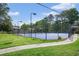 Community tennis court surrounded by green grass and tall trees in a fenced-in area at 6851 Roswell Rd # K-23, Atlanta, GA 30328