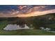 Aerial view featuring a pond and a golf course with surrounding trees and a colorful sunset at 237 Laurel Vista Dr, Canton, GA 30114