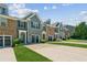 View of townhomes, each with an attached garage and manicured lawn at 5221 Sherwood Way, Cumming, GA 30040
