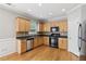 Kitchen with wooden floors, stainless steel dishwasher, and black gas range at 5221 Sherwood Way, Cumming, GA 30040
