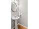 Stylish powder room featuring a pedestal sink, an oval mirror, and hardwood floors at 5221 Sherwood Way, Cumming, GA 30040