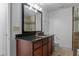 A bathroom featuring a dark granite-topped vanity, a large mirror, and a tiled shower at 1102 Madison Ln # 1102, Smyrna, GA 30080