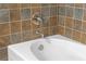 Close up of a pristine white bathtub with stylish, multicolored tile surround and stainless steel fixtures at 1102 Madison Ln # 1102, Smyrna, GA 30080