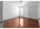 A bedroom showcasing hardwood floors, white walls, a window, and a double-door closet at 1102 Madison Ln # 1102, Smyrna, GA 30080