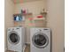 Bright laundry room with white washer and dryer and shelving for supplies at 5805 Fielding Ct, Cumming, GA 30041