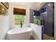 Bright bathroom showcasing a soaking tub beneath a window and a glass-enclosed blue-tiled shower at 7925 Silversmith Dr, Cumming, GA 30028