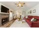 Cozy living room with brick fireplace, ceiling fan, and comfortable red couch on stylish white rug at 7925 Silversmith Dr, Cumming, GA 30028