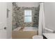 Bathroom with tub and shower featuring mosaic tiles, neutral tile, and white fixtures at 239 Kings Hwy, Decatur, GA 30030