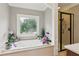 Bright bathroom features a soaking tub with decorative window and a glass-enclosed shower at 5945 Bannister Rd, Cumming, GA 30028