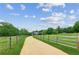 Scenic driveway leading to a beautiful home surrounded by lush greenery and a wooden fence at 5945 Bannister Rd, Cumming, GA 30028