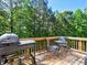 Outdoor deck featuring a barbeque grill, and table with seating overlooking trees at 475 Vinings Estates Se Dr # A03, Smyrna, GA 30126