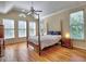 Bright bedroom featuring a four-poster bed, hardwood floors, ceiling fan, and natural light through multiple windows at 475 Vinings Estates Se Dr # A03, Smyrna, GA 30126