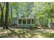 Backyard featuring mature trees, a sunroom, patio seating, and lush landscaping at 3262 Bluff Rd, Marietta, GA 30062