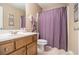 A cozy bathroom featuring a vanity with cabinet storage, a toilet, and a shower with a stylish purple curtain at 4765 Smokestone Dr, Douglasville, GA 30135