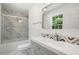 Bright bathroom featuring a marble shower, decorative mirror, and gray vanity with stylish accents at 3050 Woodland Nw Dr, Kennesaw, GA 30152
