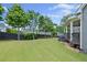 A spacious backyard featuring a lush green lawn, wooden fence, mature trees, and a covered porch at 4035 Pinebrook Cir, Cumming, GA 30028