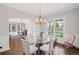 Bright dining room featuring a glass table, chandelier, and views to a home office with built-in bookcases at 4035 Pinebrook Cir, Cumming, GA 30028