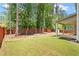 Spacious backyard features lush green grass, a wood fence, and covered patio with shade trees at 4093 Groveland Park Dr, Powder Springs, GA 30127