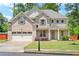 Two-story brick home featuring an attached garage, a well-manicured lawn, and mature trees at 4093 Groveland Park Dr, Powder Springs, GA 30127