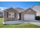 Charming single-story home with brick facade, attached garage, manicured lawn and vibrant red window shutters at 1907 Sea Oats Dr, Hampton, GA 30228