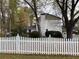 Backyard with a white picket fence surrounding the property, mature trees, and a large yard at 5440 Cameron Forest Pkwy, Johns Creek, GA 30022