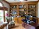Cozy home office with built-in bookshelves, desk, and a comfortable plaid armchair near a large window at 5440 Cameron Forest Pkwy, Johns Creek, GA 30022