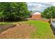 Fenced backyard with a small brick fire pit and a grassy area, surrounded by mature trees at 771 James Cir, Lawrenceville, GA 30046