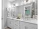 Bright bathroom featuring double sinks, quartz countertops, modern lighting, and a glimpse of the main bedroom at 250 Castleberry Station Sw Dr, Atlanta, GA 30313