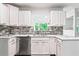Bright kitchen featuring stainless steel dishwasher, white cabinets, stone backsplash and white countertop at 4148 Kings Cswy, Ellenwood, GA 30294