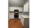 Kitchen features white cabinets, stainless appliances, and wooden floors at 401 Courtyard Ter, Woodstock, GA 30189