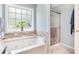 Modern bathroom featuring a jetted tub, glass shower, and stone wall accents at 1211 Fly Rod Ln, Loganville, GA 30052