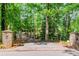 Stone pillars with statues mark the entrance to a long driveway surrounded by lush trees and greenery at 2228 Walker Dr, Lawrenceville, GA 30043
