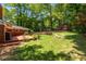 Lush backyard with a brick home, deck, mature trees, stone retaining wall, and a charming shed at 2279 Parkview Cir, College Park, GA 30337