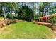 Lush backyard features a stone retaining wall, brick house, deck, and beautiful green lawn at 2279 Parkview Cir, College Park, GA 30337
