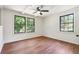 Bedroom features hardwood floors, neutral walls, and a modern ceiling fan illuminated by natural light from two large windows at 3708 Canadian Way, Tucker, GA 30084