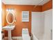 Traditional bathroom with pedestal sink, oval mirror, and orange-painted walls at 1420 Arblay Pl, Loganville, GA 30052