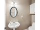 Bathroom features a pedestal sink, oval mirror, and a toilet at 1420 Arblay Pl, Loganville, GA 30052
