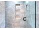 Modern shower featuring sleek gray tiling, built-in shelving niche, and a frameless glass door at 1621 Dixie Rd, Covington, GA 30014