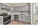 Modern kitchen features stainless steel appliances, gray cabinetry, marble backsplash, and hardwood floors at 3910 Meeting St, Duluth, GA 30096