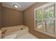 Cozy bathroom featuring a tub, toilet, and shuttered window at 4930 Forestglade Ct, Tucker, GA 30087
