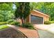 Attached two-car garage with a brick exterior and a paved driveway surrounded by greenery at 4930 Forestglade Ct, Tucker, GA 30087