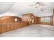 Open bonus room features neutral carpet, wood paneling and ceiling fans at 1795 Hutcheson Ferry Rd, Whitesburg, GA 30185