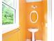 Bathroom with a pedestal sink, oval mirror, and a window overlooking lush greenery at 21 Wisteria Run, Hiram, GA 30141