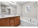 Bathroom showcasing double sinks, an oval window, and a luxurious soaking tub at 2647 Sardis Chase Ct, Buford, GA 30519