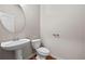 Powder room with a modern pedestal sink, round mirror, and wood flooring at 2647 Sardis Chase Ct, Buford, GA 30519
