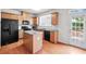 Bright kitchen featuring wood cabinets, granite countertops, black appliances, kitchen island, and a door to the backyard at 2647 Sardis Chase Ct, Buford, GA 30519