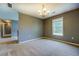 Neutral room with beige carpet features a window, chandelier and adjacent room at 2821 Highway 11, Mansfield, GA 30055